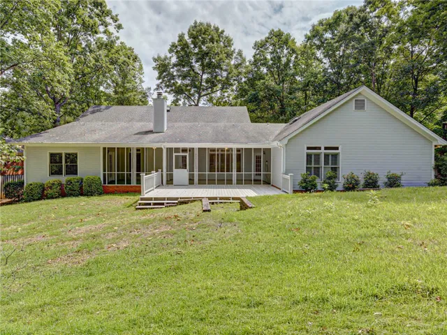 A spacious screened-in porch and deck extend along the rear of this home, offering serene views of the surrounding trees.