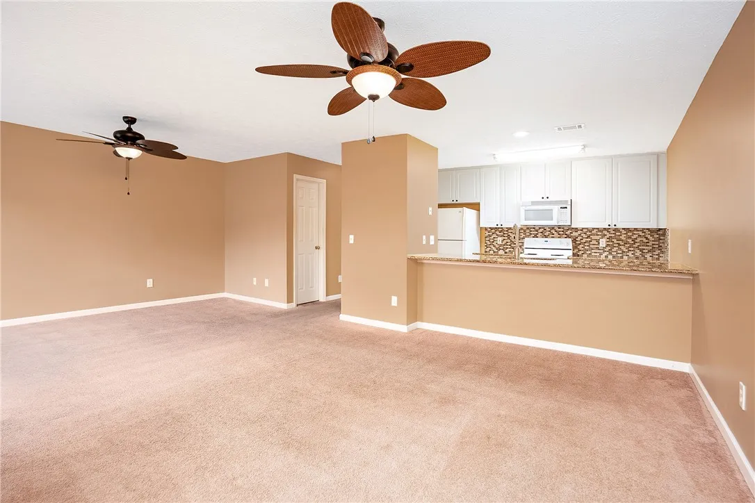 An open concept living area features soft carpeting and integrated kitchen space.