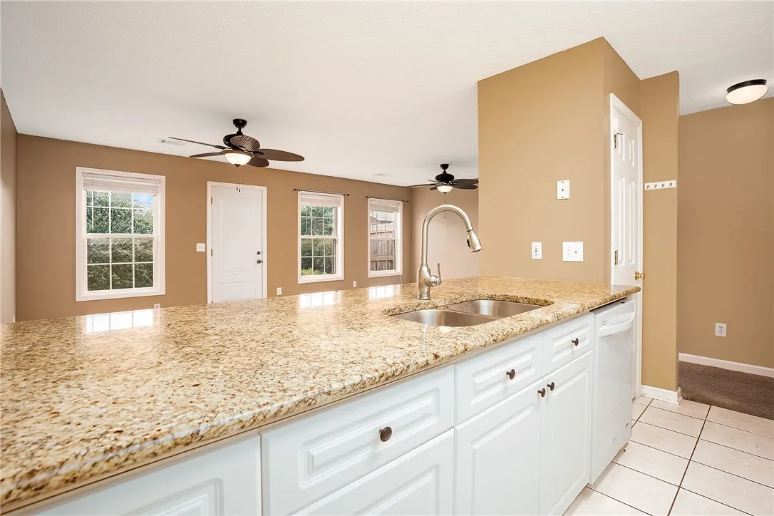 A well-lit kitchen featuring a granite island and white cabinetry, ready for culinary endeavors.
