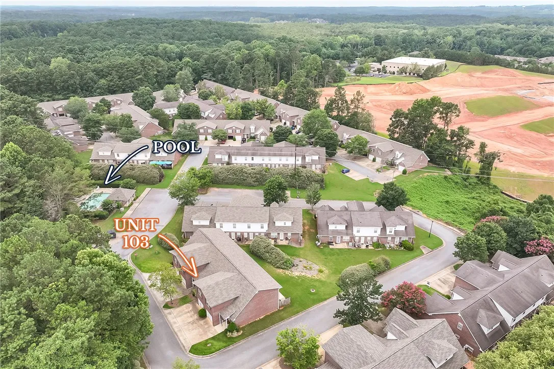 An aerial perspective showcases the community pool, surrounded by mature trees, and nearby townhome residences.