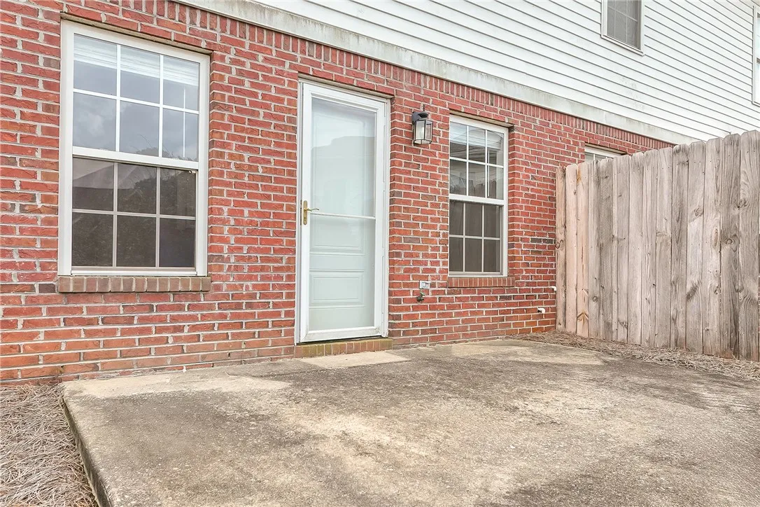 A private concrete patio adjoins this brick-and-siding exterior, framed by a sturdy wood fence.