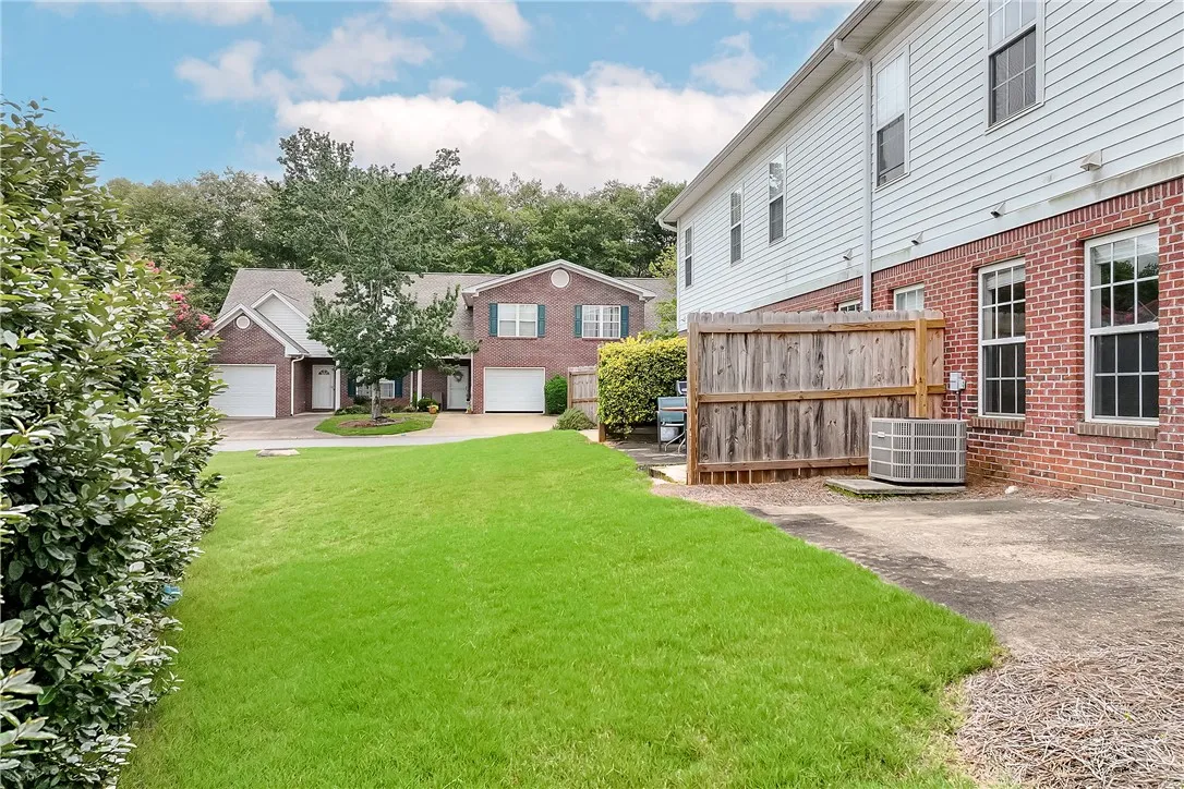 Green lawns frame a row of inviting brick townhomes, offering comfortable living with private garages.