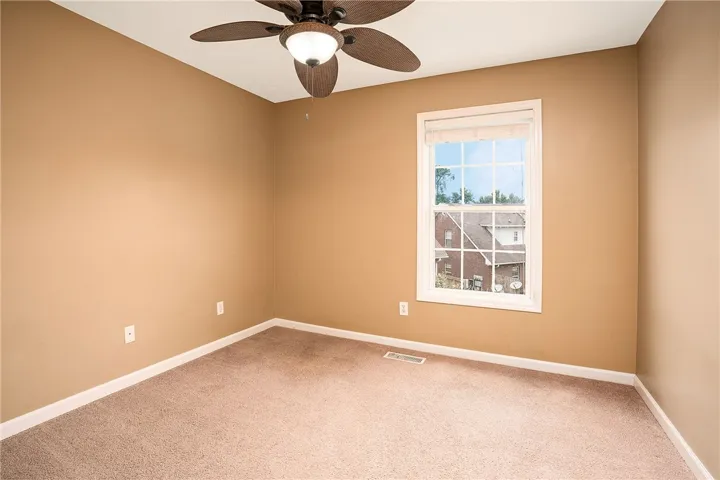 Comfortable bedroom offers soft carpet flooring and a ceiling fan, ensuring year-round comfort.