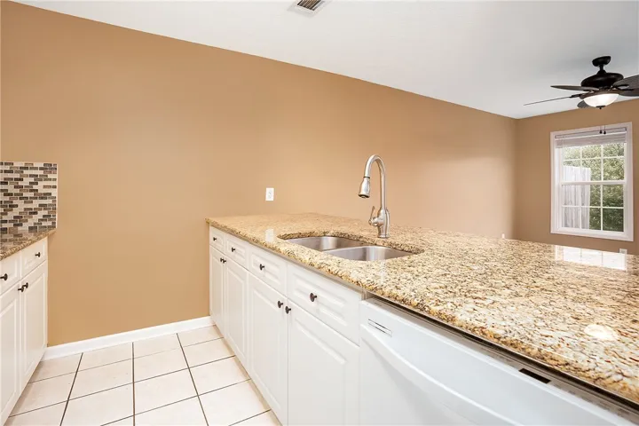 Granite counters and stainless double sink define this functional kitchen island with integrated dishwasher.