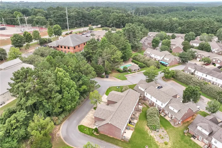 Discover a tranquil community with a refreshing pool, nestled among mature trees and winding roads.