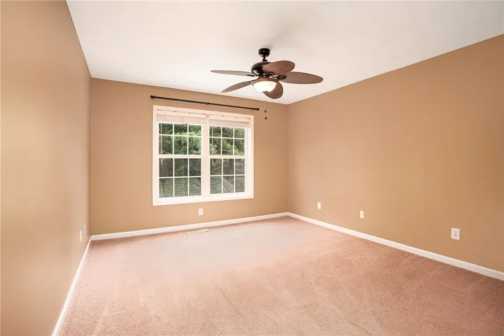 A quiet retreat with a window overlooking nature, enhanced by a decorative ceiling fan.