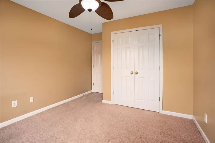 A well-lit room featuring ample closet space and comfortable flooring.
