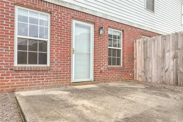 A private concrete patio adjoins this brick-and-siding exterior, framed by a sturdy wood fence.