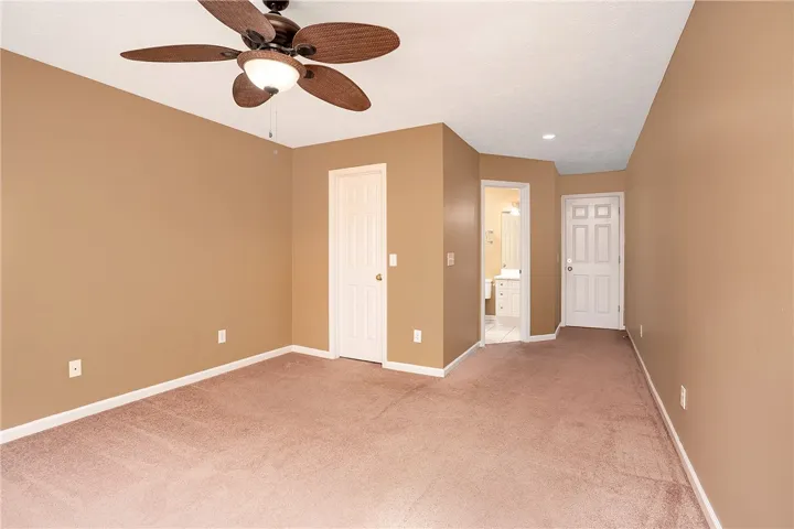 A comfortable bedroom features plush carpeting and a modern ceiling fan for year-round comfort.