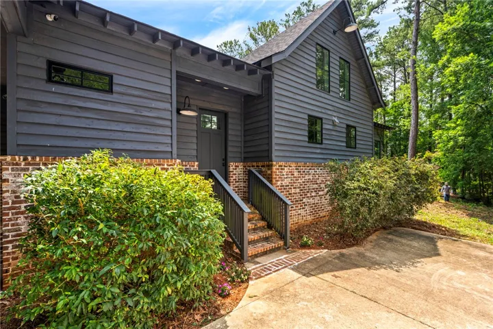 A charming dwelling with dark siding, brick foundation, and natural landscaping provides a warm welcome.