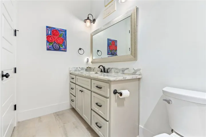 Elegant gray vanity, marble counter, and tiled floors define this clean bathroom.
