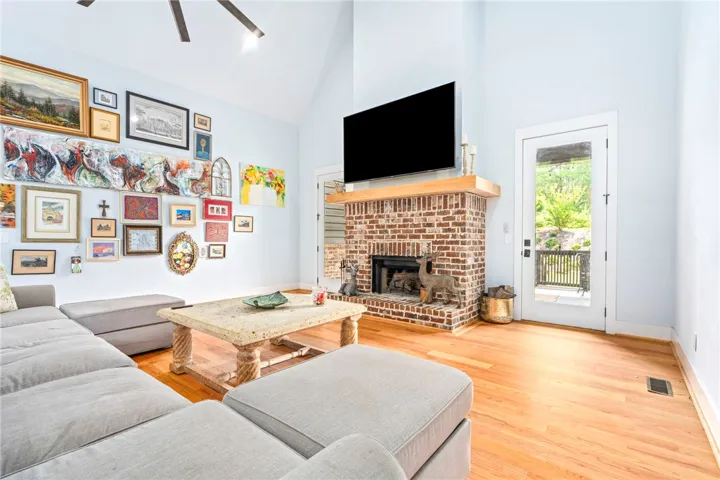 A striking brick fireplace grounds this comfortable living area with gleaming hardwood flooring and vaulted ceilings.
