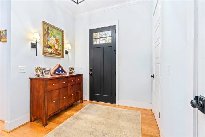 A well-lit entry hall features rich hardwood flooring and a stylish black front door.