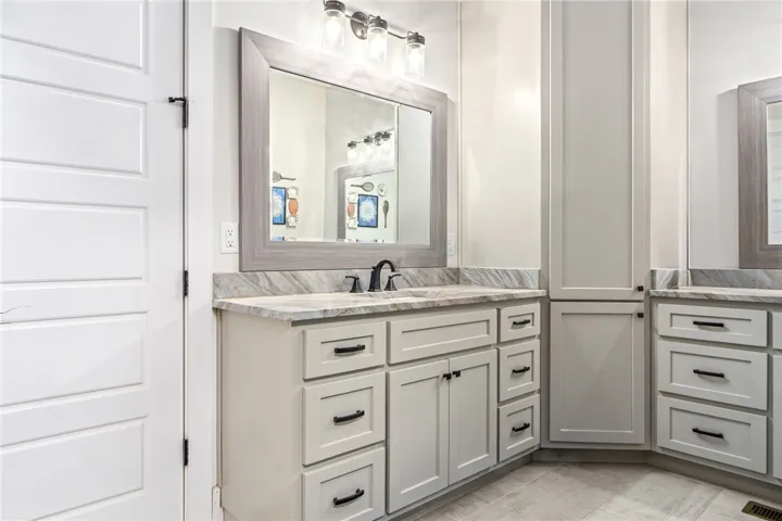 A well-appointed bathroom features extensive cabinet storage and elegant stone counters.