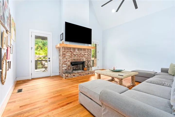 A striking brick fireplace grounds this airy living space with warm hardwood floors and a lofty vaulted ceiling.