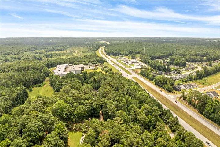 An aerial perspective reveals a vast forested landscape with residential areas and a main road traversing the scene.