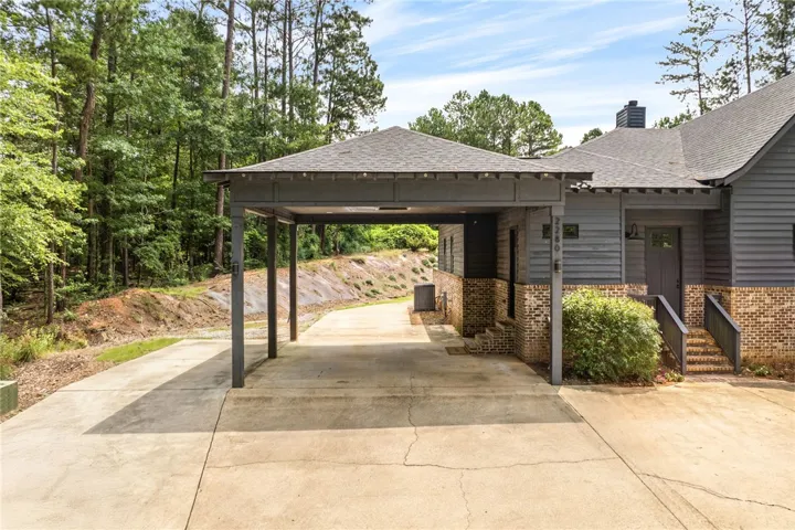 A welcoming carport provides shelter, complementing the home's dark siding and brick facade.
