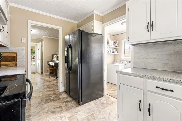 A functional kitchen provides direct access to a dedicated laundry area and an adjacent living space.