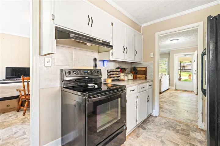 A compact kitchen with functional appliances and white cabinetry provides a practical cooking space.