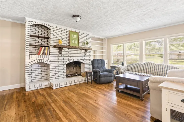 A classic brick fireplace with built-in shelving anchors this living space, offering warmth and integrated storage.