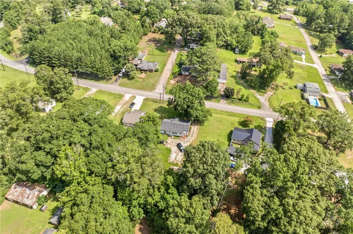 An aerial perspective reveals a verdant landscape with homes nestled amidst mature trees and accessible roadways.