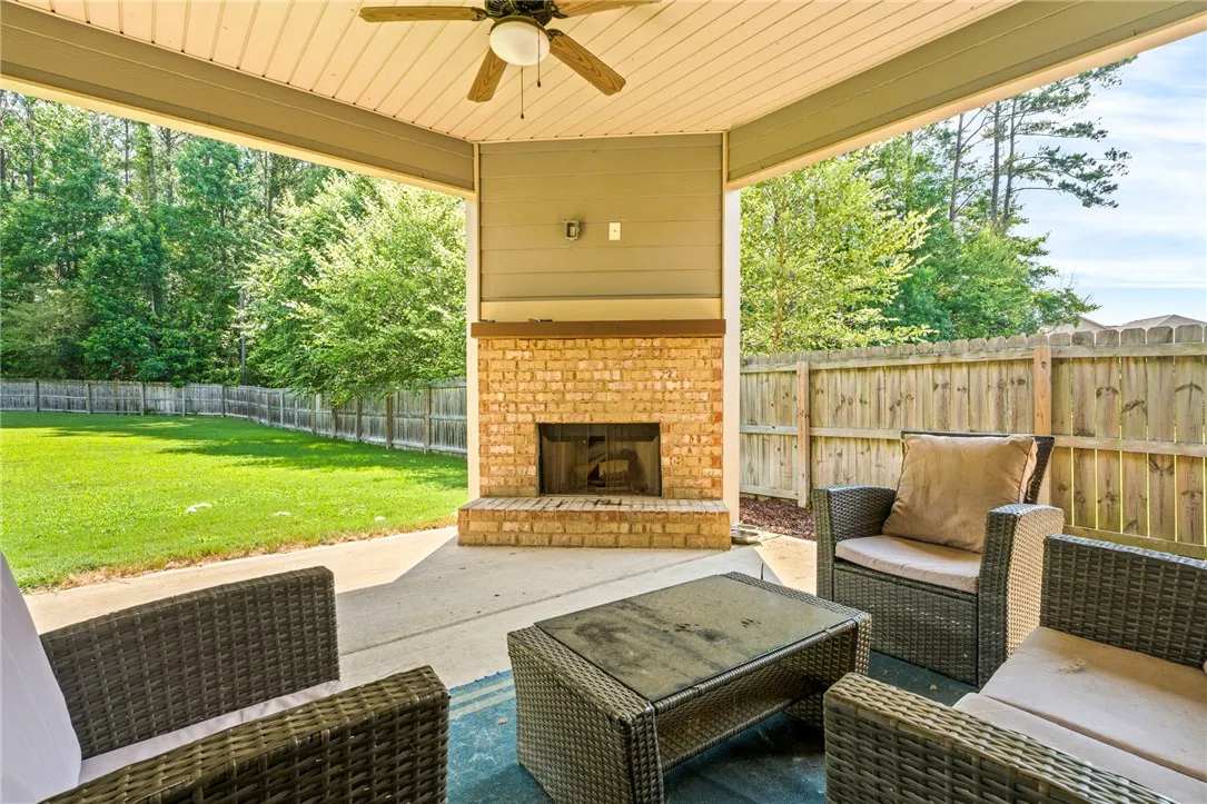 An inviting outdoor living space features a brick fireplace for cozy gatherings and a spacious, fenced backyard.