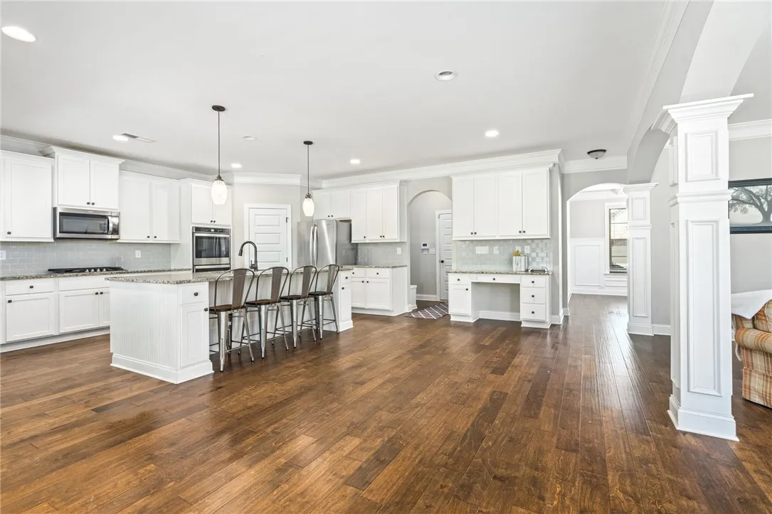 A sprawling kitchen with a grand island, abundant cabinetry, and polished hardwood flooring beckons culinary creativity.