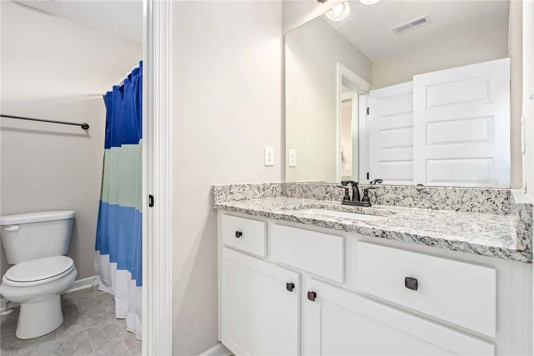 A well-appointed bath features a sleek vanity with granite counters and contemporary flooring.