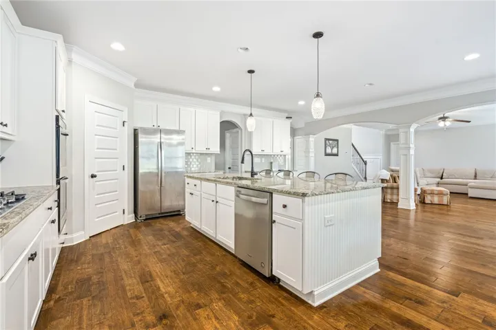 An open concept kitchen features stainless steel appliances, granite countertops, and hardwood flooring.