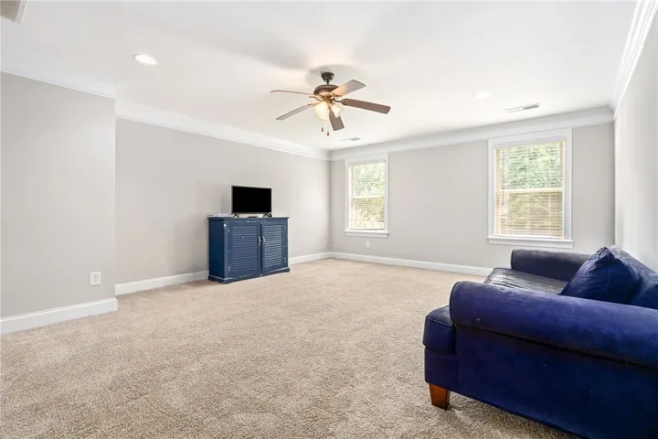 An inviting secondary living area features soft carpeting, recessed lighting, and a ceiling fan for comfort.