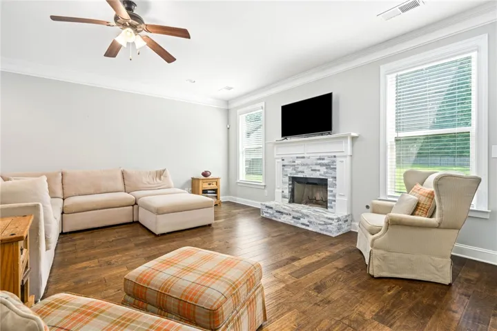 A well-appointed living room offers a stone-tiled fireplace and rich hardwood flooring, perfect for gatherings.