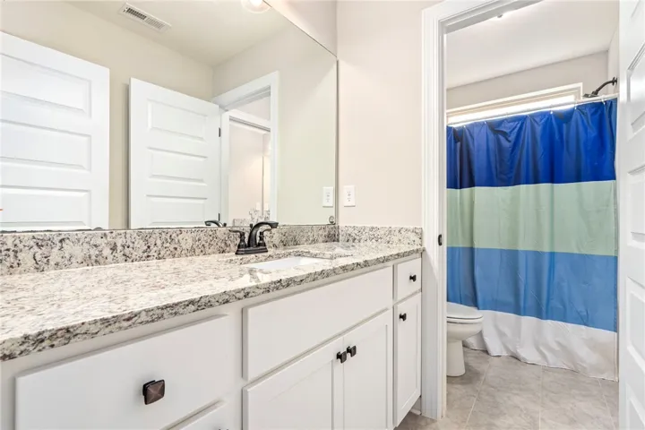 Granite counters and bright cabinetry define this well-appointed bathroom vanity.