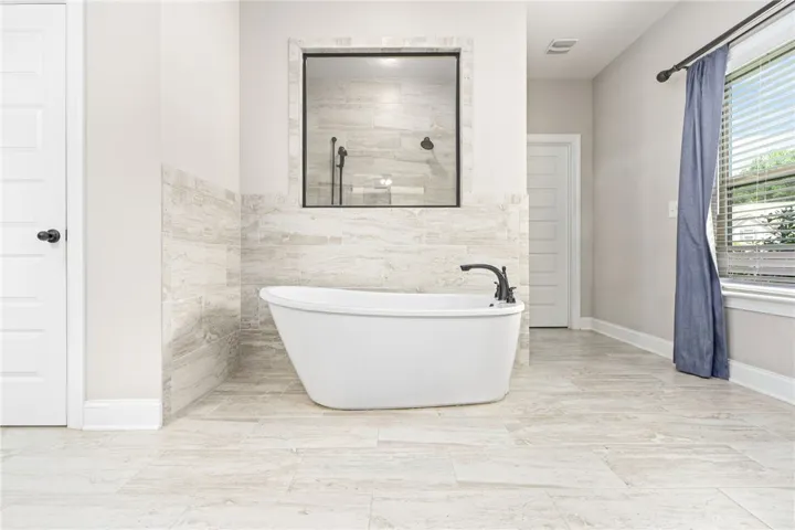 Indulge in relaxation with this contemporary freestanding bathtub and tiled shower enclosure.