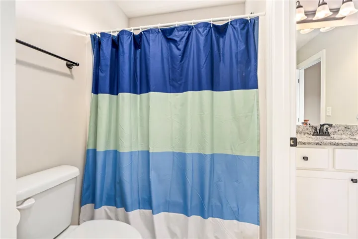 A vibrant shower curtain brightens this well-appointed bathroom with a sleek vanity.