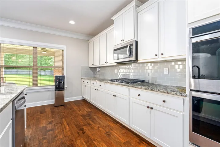 A well-appointed kitchen showcasing rich hardwood floors and sleek, light-colored cabinetry.