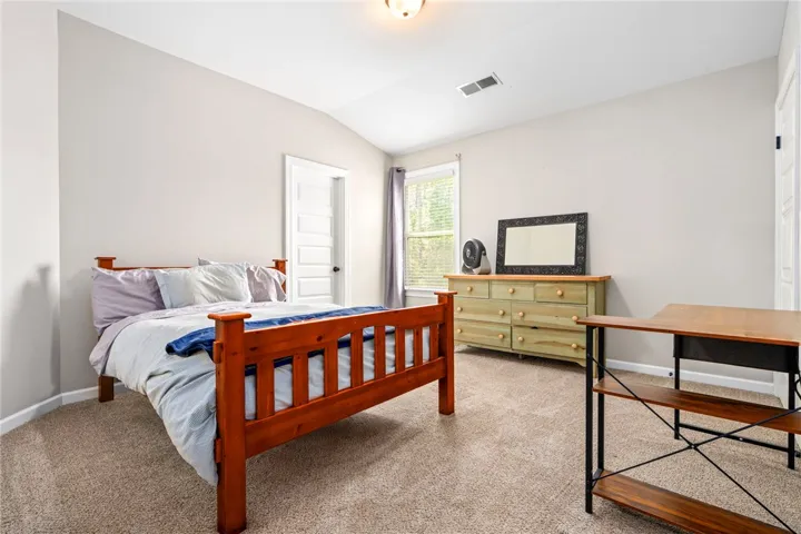 A comfortable bedroom features plush carpeting and a high vaulted ceiling, perfect for peaceful slumber.