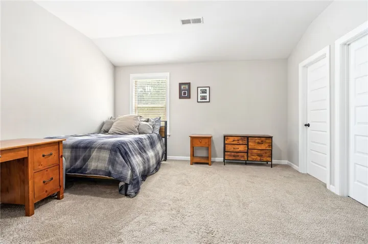 A well-lit bedroom features plush carpeting and a sloped ceiling, offering a cozy and comfortable living space.