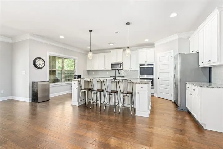 A pristine culinary space boasts rich hardwood floors and an inviting central island with breakfast bar seating.