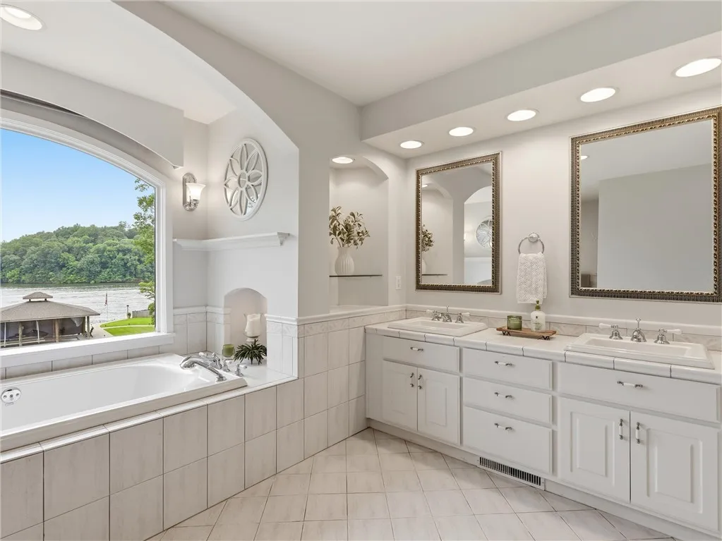 Luxurious bathroom offers a serene lake view from the deep soaking tub, complemented by a spacious double vanity.