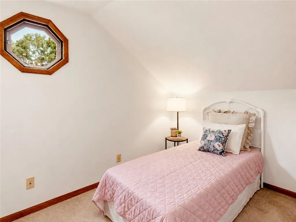 An octagonal window bathes this cozy bedroom in natural light, creating a serene and inviting atmosphere.