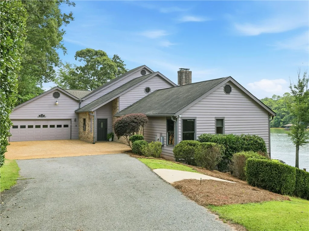 Lakeside living meets modern convenience with a spacious attached garage, separate driveway for a golfcart and picturesque water views.
