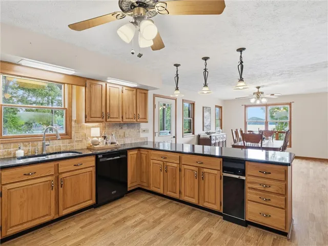 A well-lit kitchen with natural wood cabinetry and granite countertops opens up to the adjacent dining area.  The window above the sink also provides a great view of the lake and boathouse.