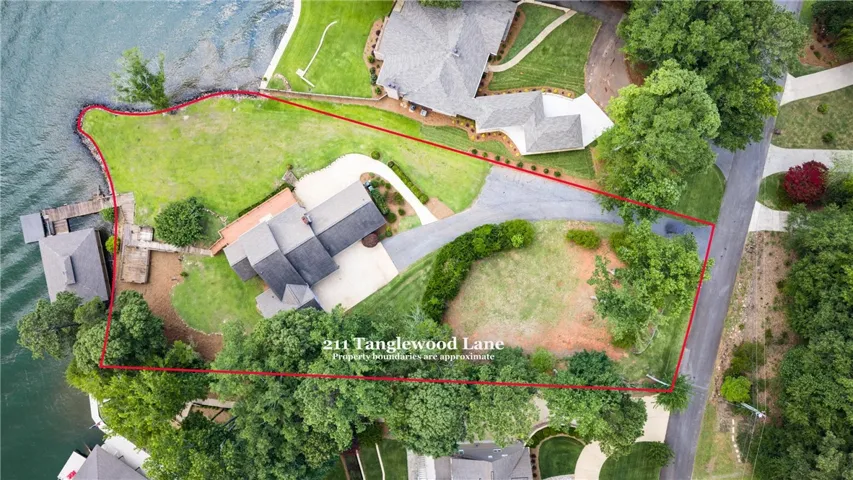An aerial perspective reveals the expansive waterfront property, featuring a private dock and mature trees.  Lot size is .92 acres.