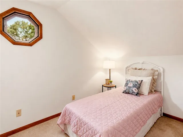 An octagonal window bathes this cozy bedroom in natural light, creating a serene and inviting atmosphere.