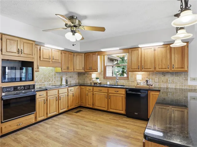 Lots of warm wood cabinetry and dark countertops define this spacious, well-lit kitchen, ideal for culinary creations and great storage.