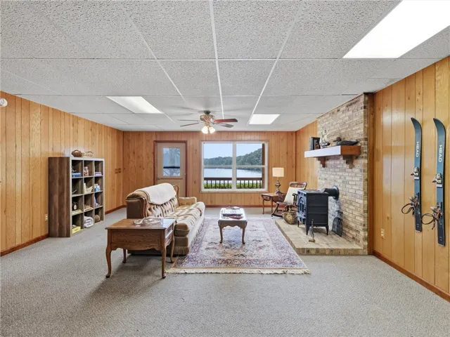 This spacious downstairs living room has lake views, wood-paneled walls, and a cozy fireplace creating a rustic retreat.