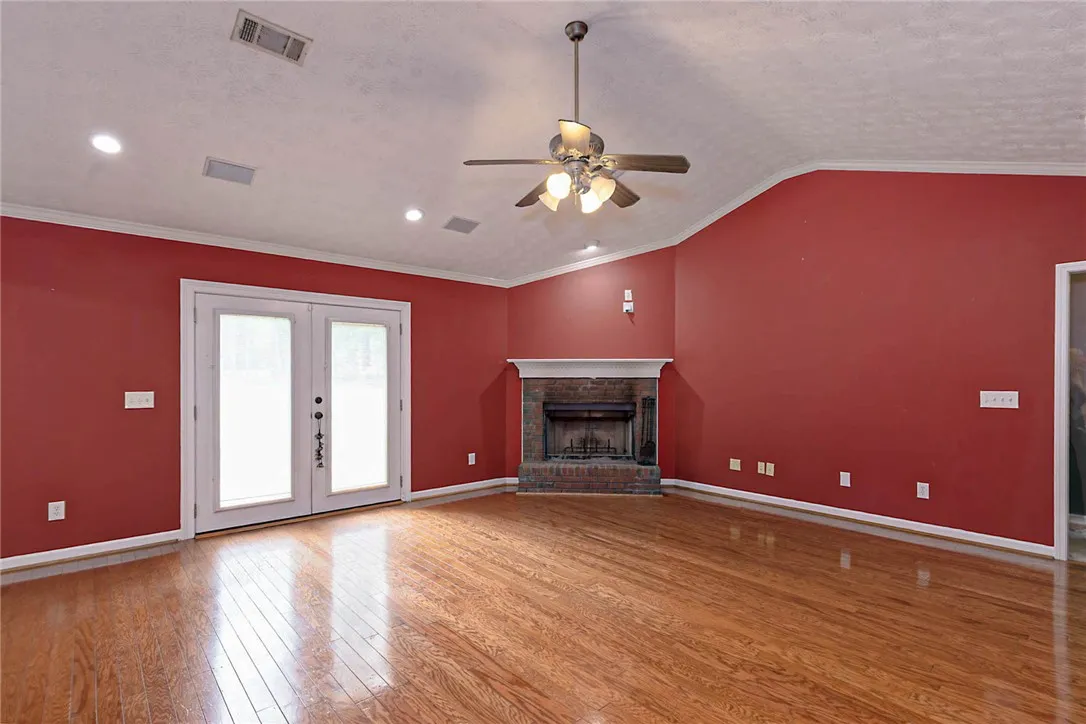 Warm wood flooring extends throughout this inviting living space, centered around a cozy brick fireplace.