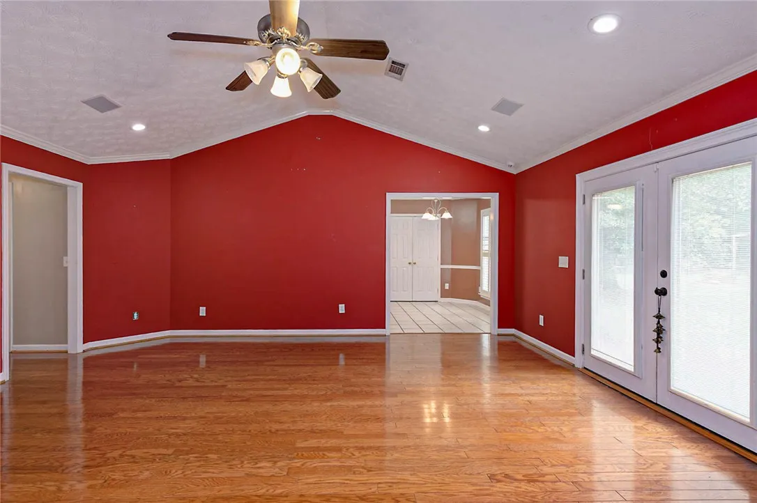 Varnished wood floors reflect light in this spacious living area with tall vaulted ceilings and bright white trim.