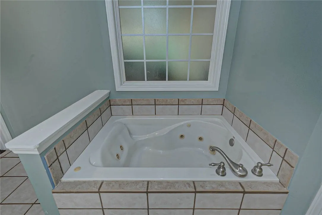 Relax in this inviting jetted tub, nestled under a privacy window and surrounded by tile.