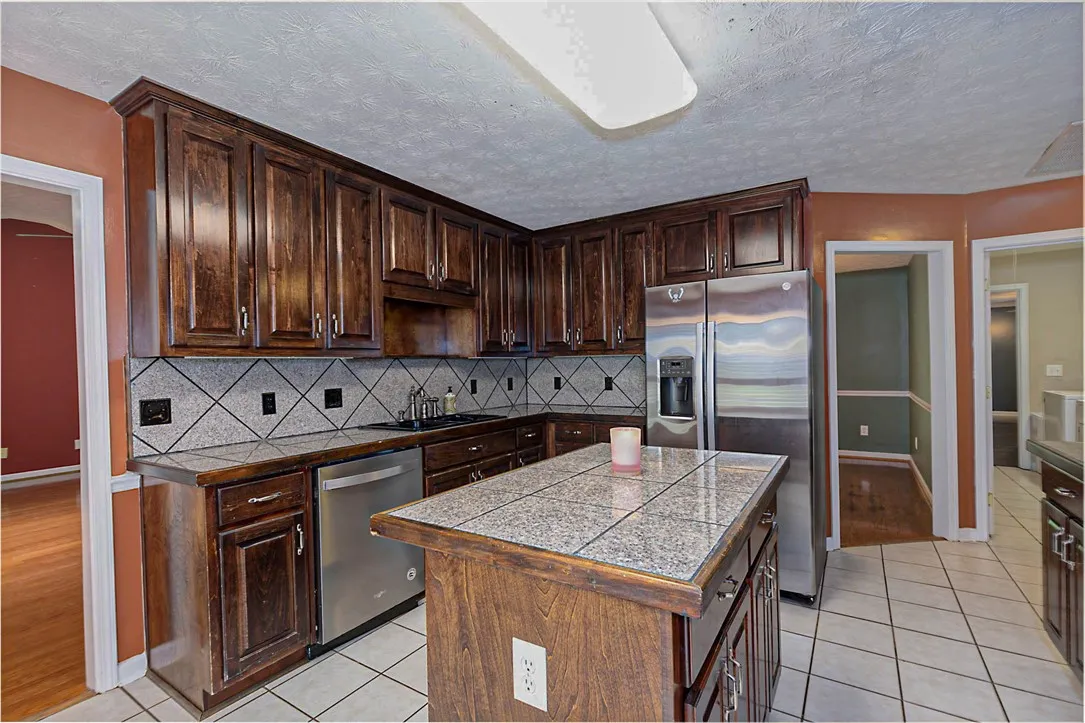 A well-appointed kitchen features rich wood cabinetry, tile flooring, and modern stainless steel appliances.